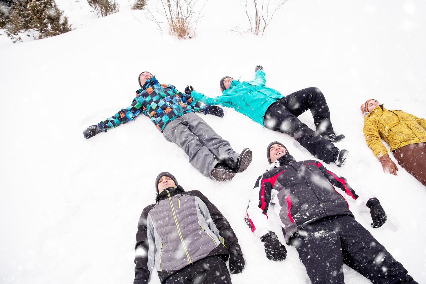 gruppo di giovane persone posa su neve e fabbricazione neve angelo foto
