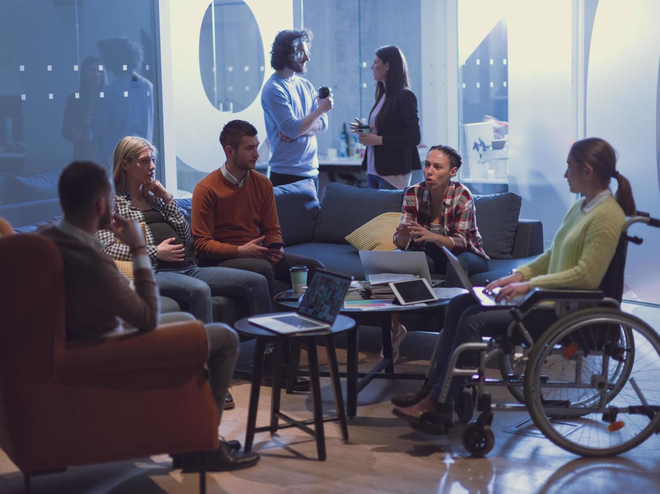 handicappato donna d'affari nel un' sedia a rotelle su incontro con sua diverso attività commerciale squadra di brainstorming a ufficio foto