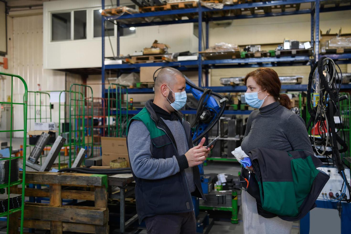 industriale lavoratori con viso maschere protetta contro corona virus discutere di produzione nel fabbrica. persone Lavorando durante covid-19 pandemia. foto