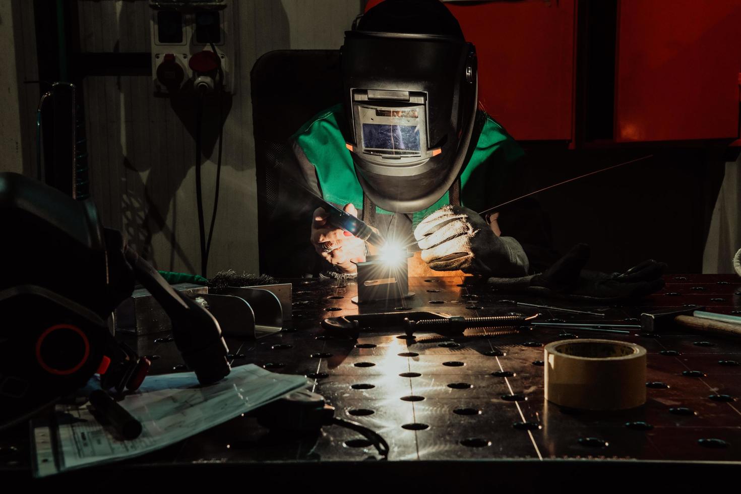 professionale saldatore esegue opera con metallo parti nel fabbrica, scintille e elettricità. industria lavoratore striscione. foto