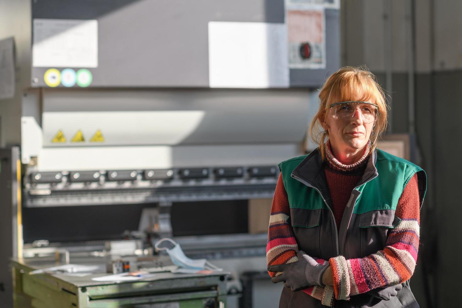 ritratto di un' donna in piedi nel davanti di un' cnc macchina nel occhiali e Lavorando nel un' moderno metallo produzione e in lavorazione fabbrica foto