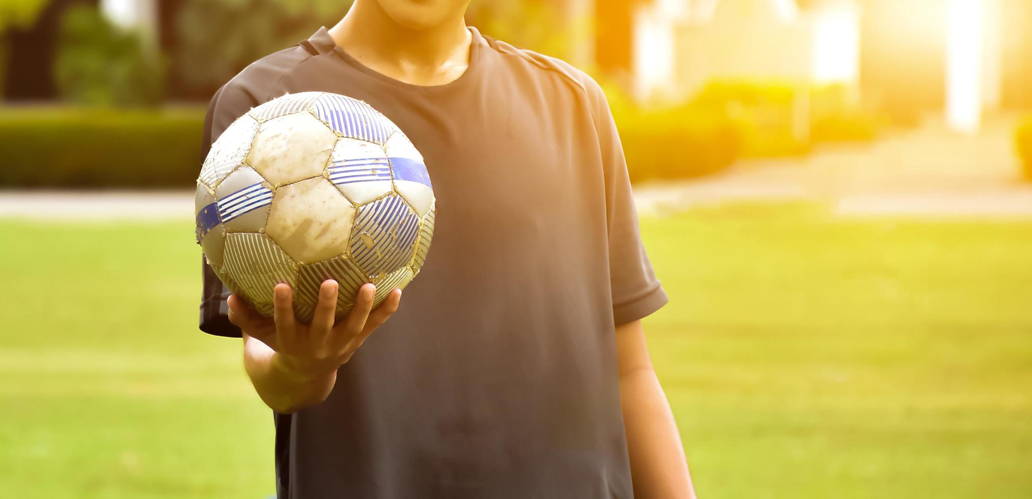 un vecchio calcio Tenere nel mano di giocatore, morbido e selettivo messa a fuoco su calcio, luce del sole modificato sfondo. foto