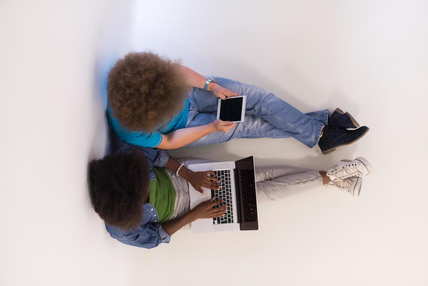 multietnico coppia seduta su il pavimento con un' il computer portatile e tavoletta superiore Visualizza foto