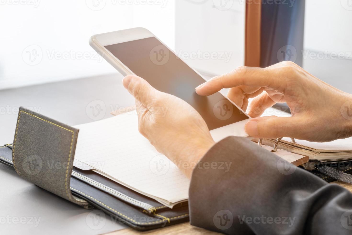 attività commerciale donna utilizzando mobile Telefono con vuoto progettista libro Aperto su desktop. foto