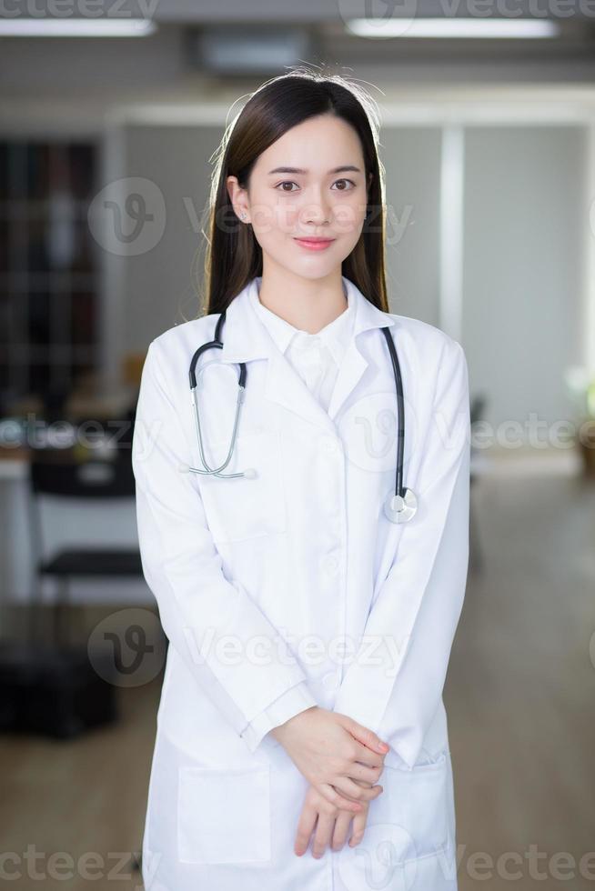 il medico asiatico della donna si leva in piedi con sicurezza e sorride. foto
