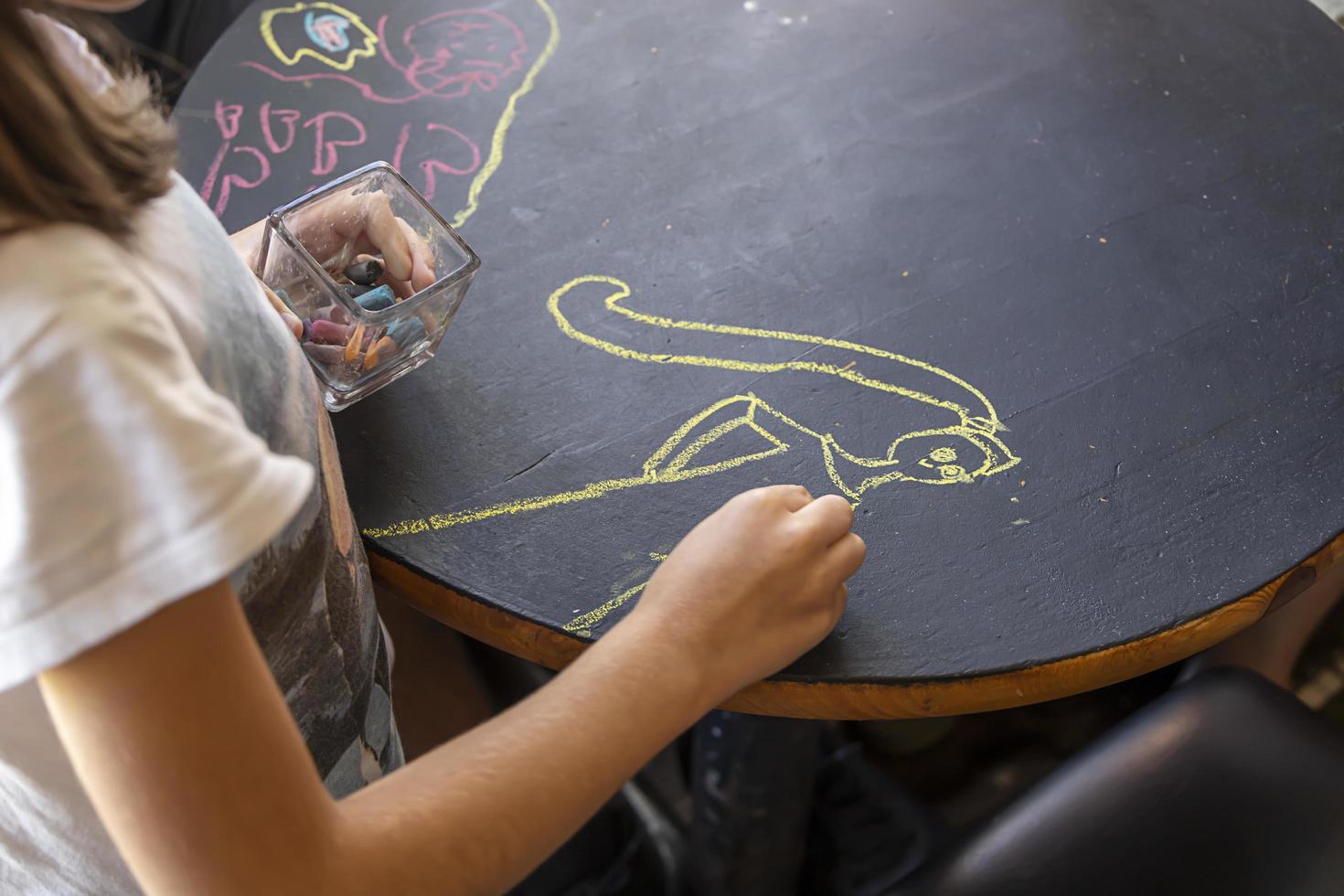 bambino disegno su un' lavagna tavolo nel un' ristorante foto