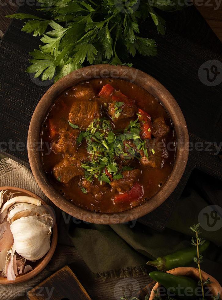 un'immagine ravvicinata di uno stufato di carne ed erbe aromatiche in background foto