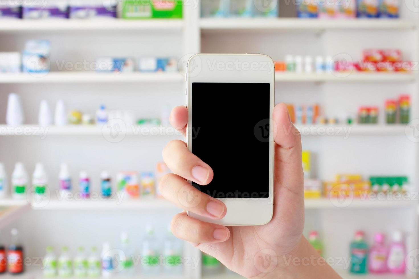 mano che tiene smart phone in farmacia foto