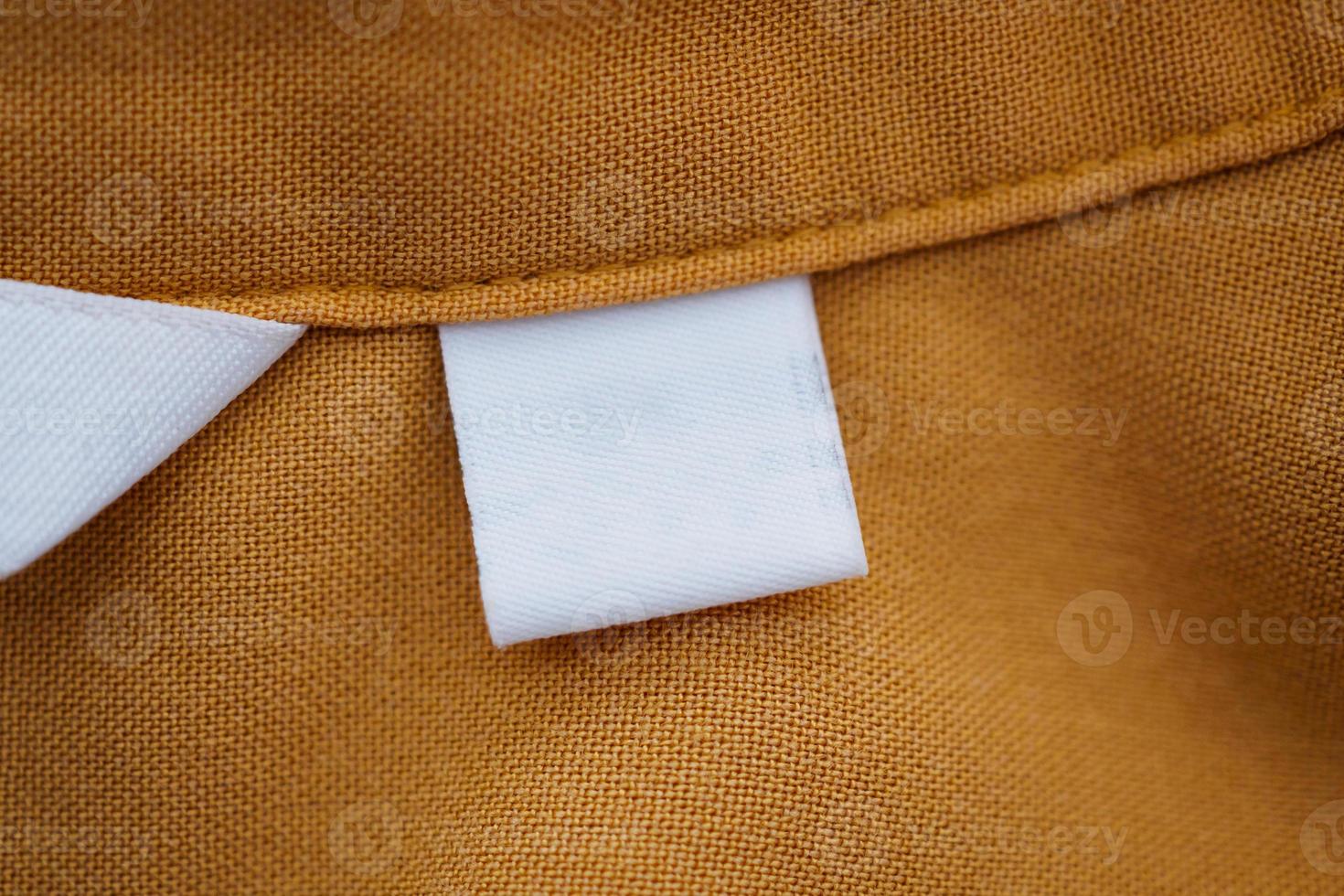 etichetta di abbigliamento in bianco bianco su sfondo marrone camicia foto