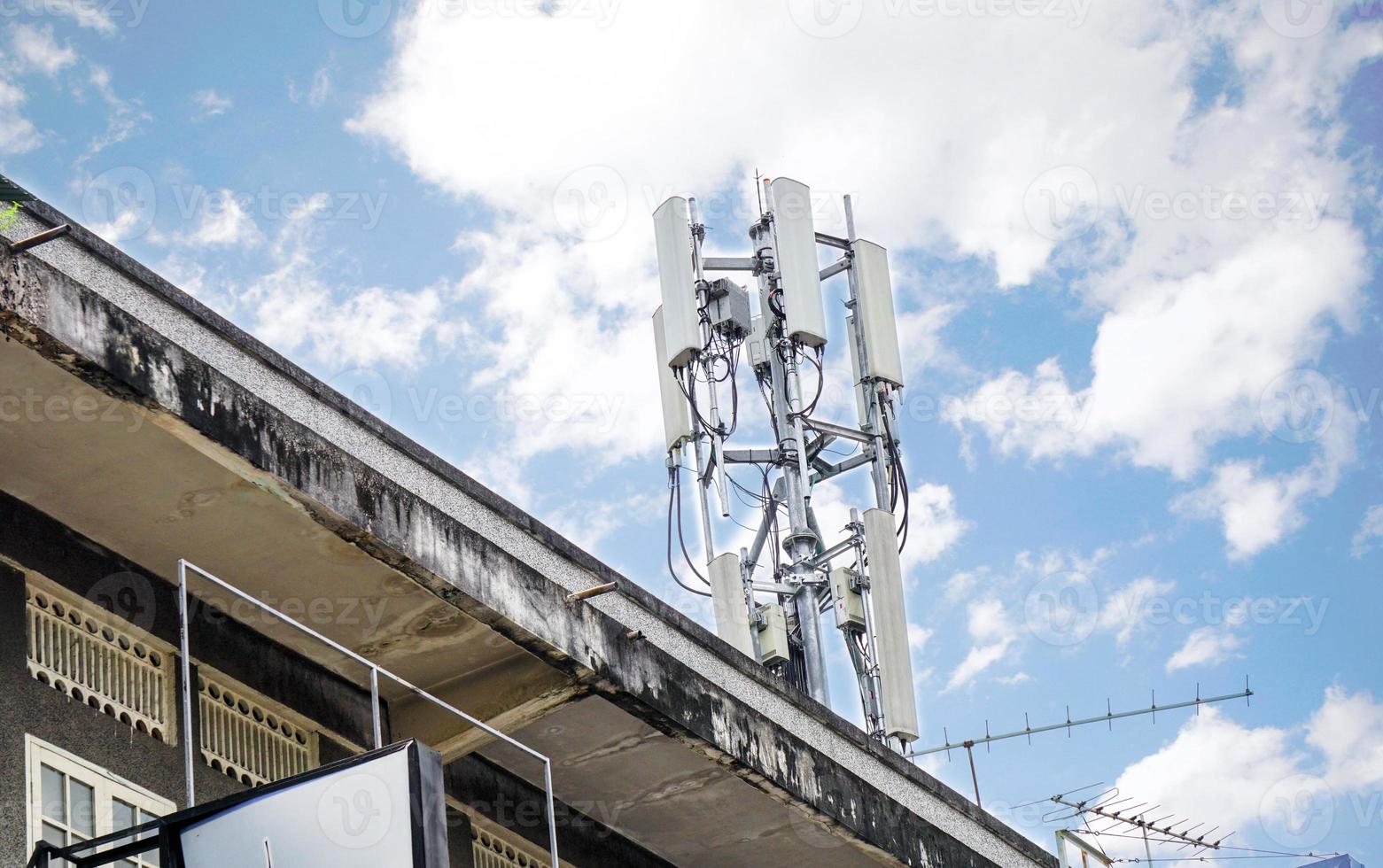 Guarda su Visualizza di comunicazione Torre con antenne su il superiore di edificio e luminosa blu cielo con grande nuvole sfondo. foto