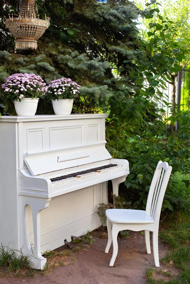 pianoforte bianco e sedie nel giardino estivo foto
