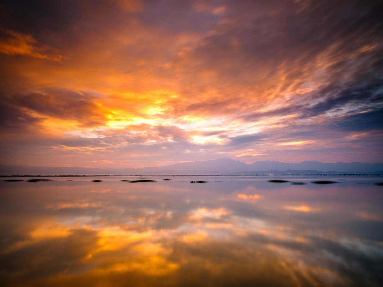 tramonto che riflette in acqua ferma foto