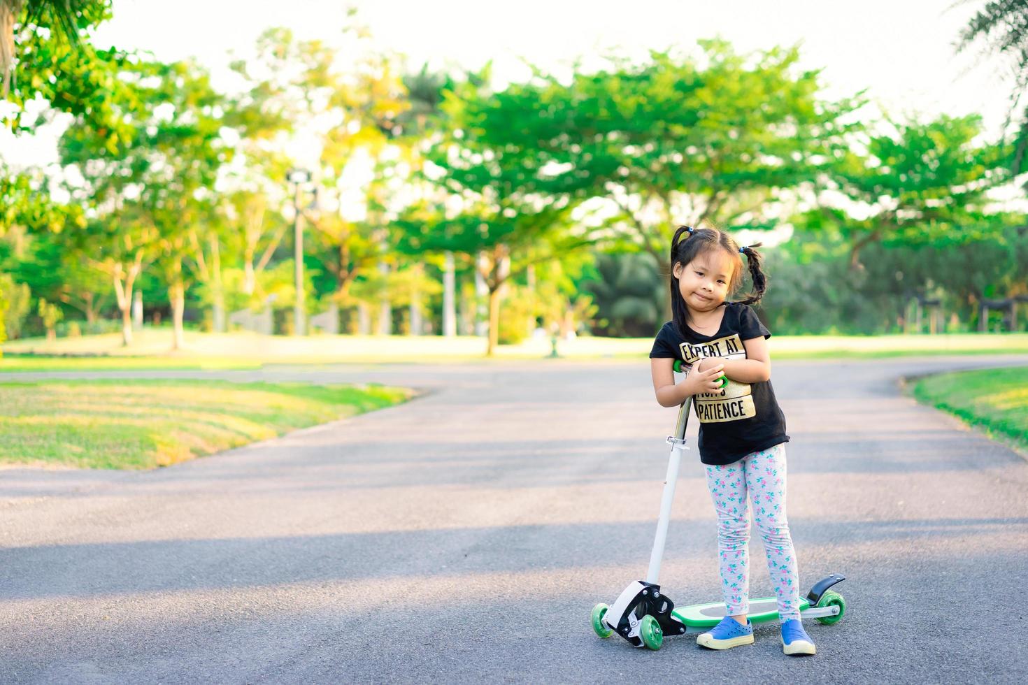 giovane ragazza asiatica cavalca scooter nel parco foto