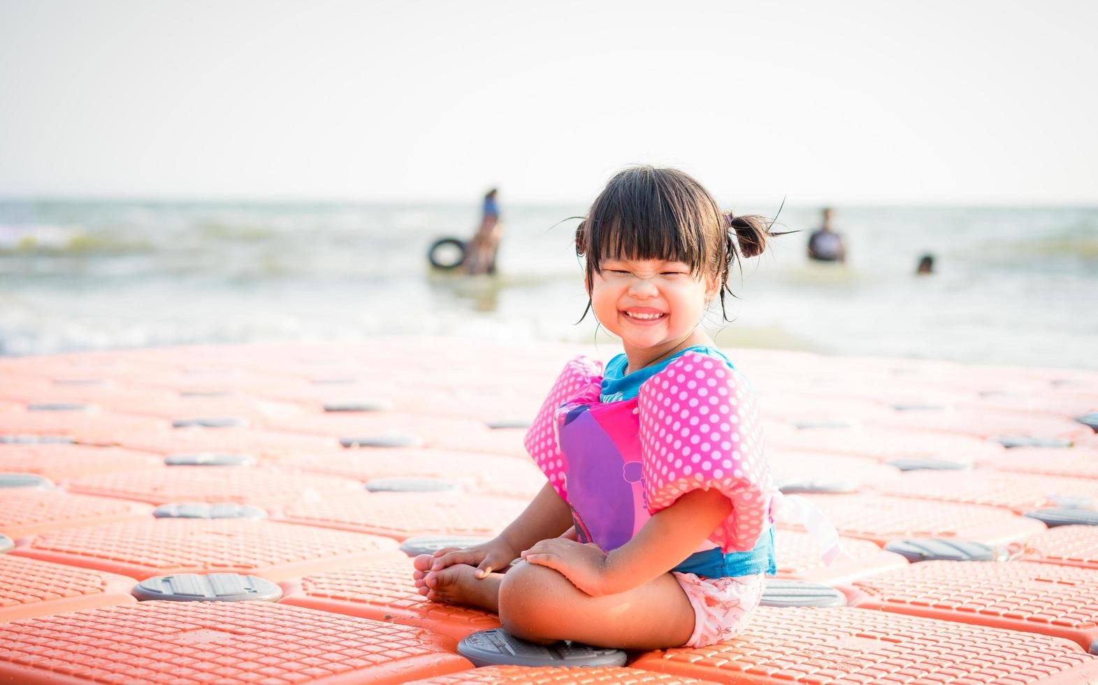 piccola ragazza asiatica che sorride sulla spiaggia foto