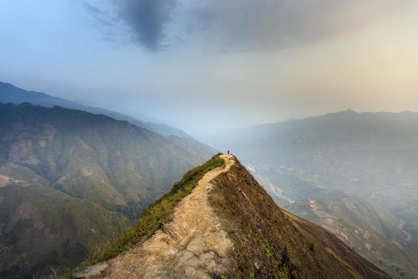 persona sul sentiero che domina le montagne foto