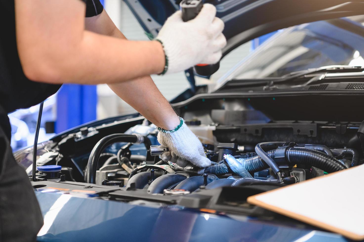 il meccanico maschio tiene la torcia elettrica per esaminare l'auto foto