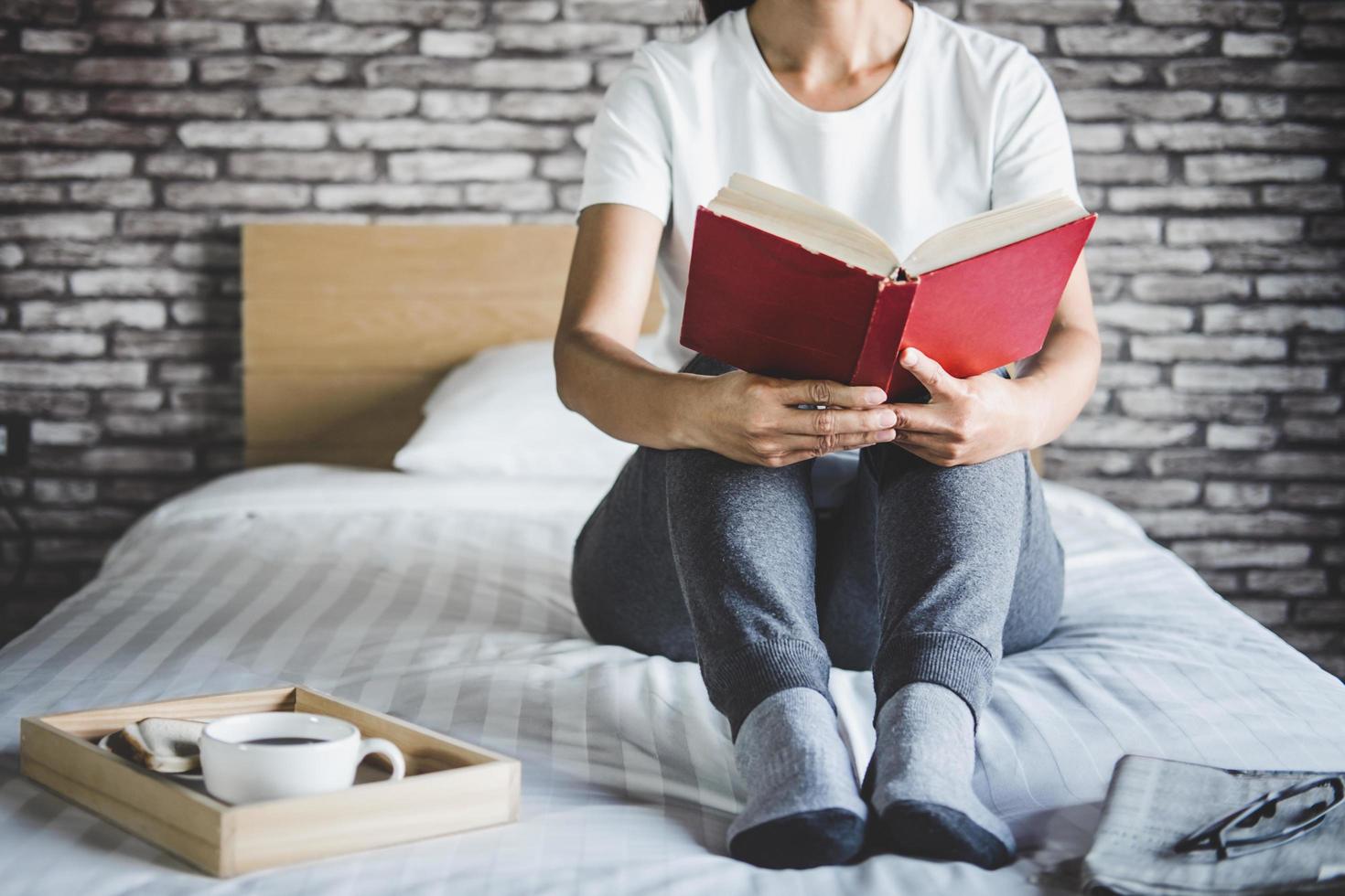 giovane donna che gode di un libro a letto foto