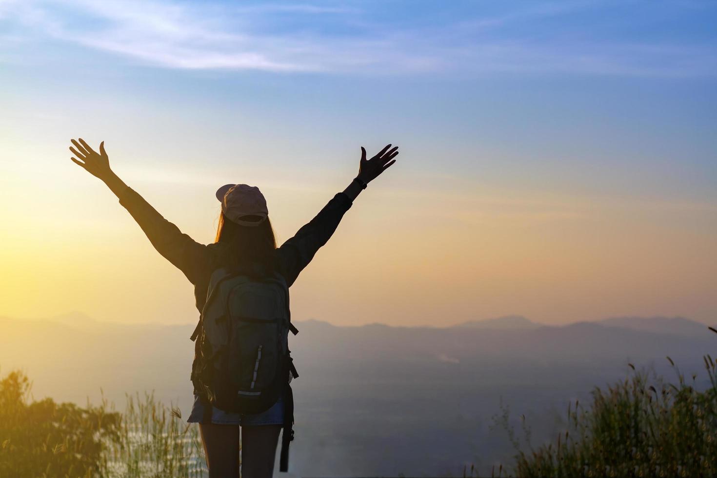 la donna ha alzato le braccia sul picco di montagna foto