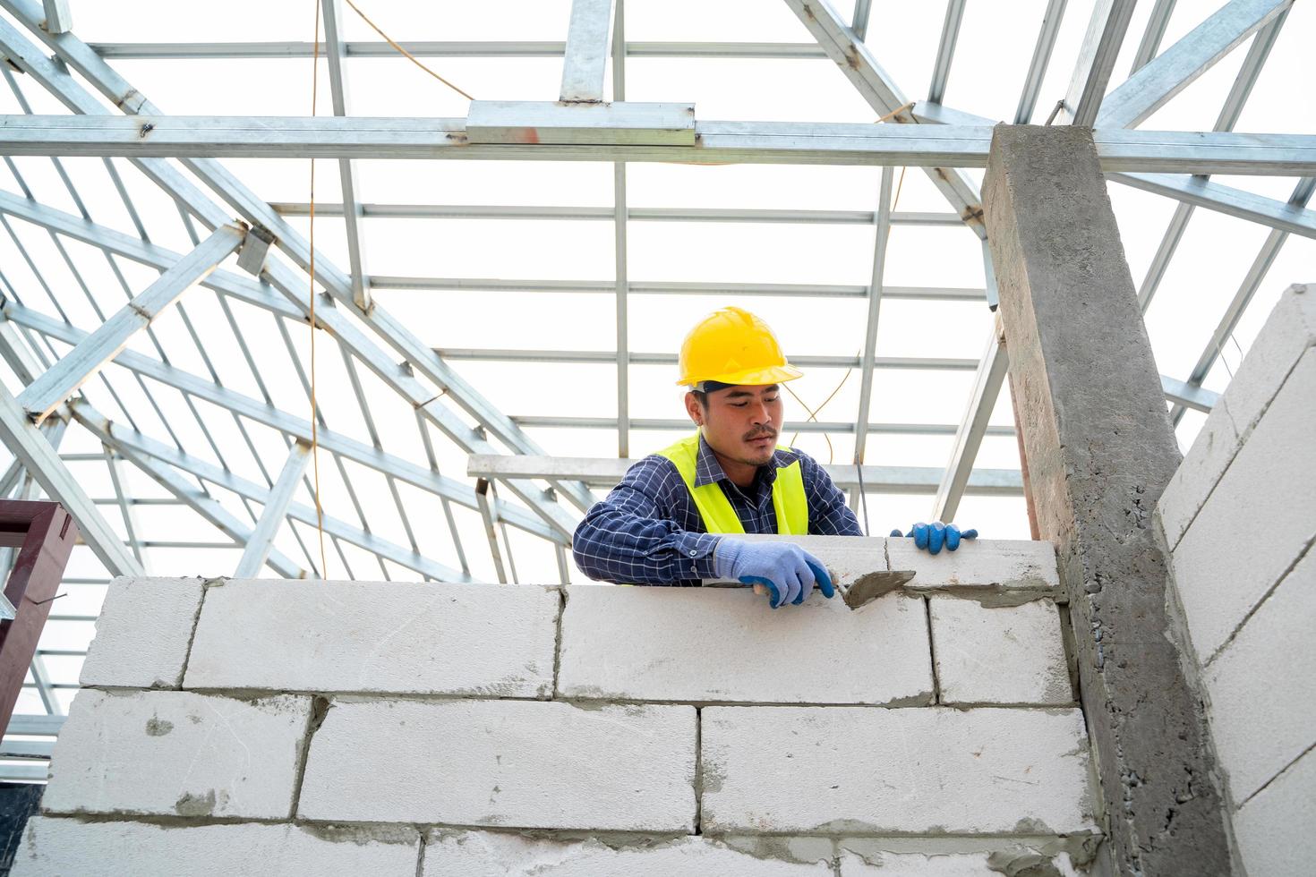 muratore che costruisce muro di mattoni foto