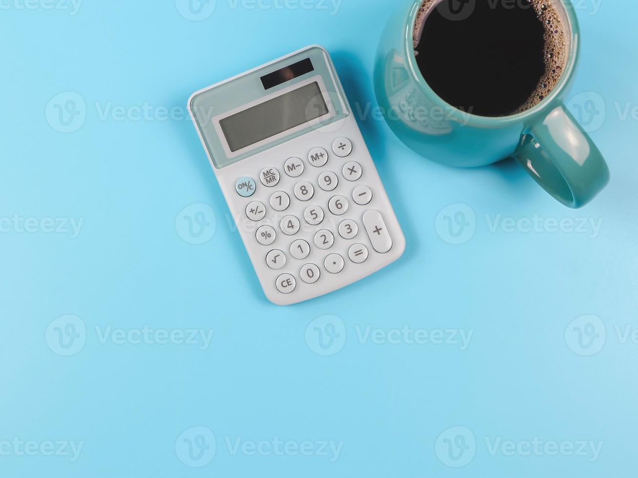 piatto posare di blu calcolatrice e blu tazza di nero caffè su blu sfondo con copia spazio. foto