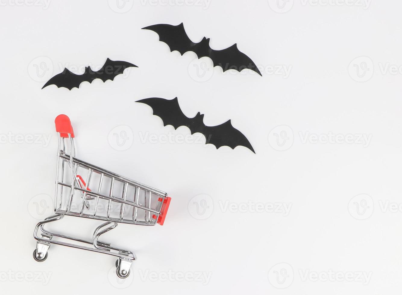piatto posare di shopping carrello, Halloween decorazioni, nero carta pipistrelli su bianca sfondo con copia spazio. Halloween vacanza shopping concetto. foto