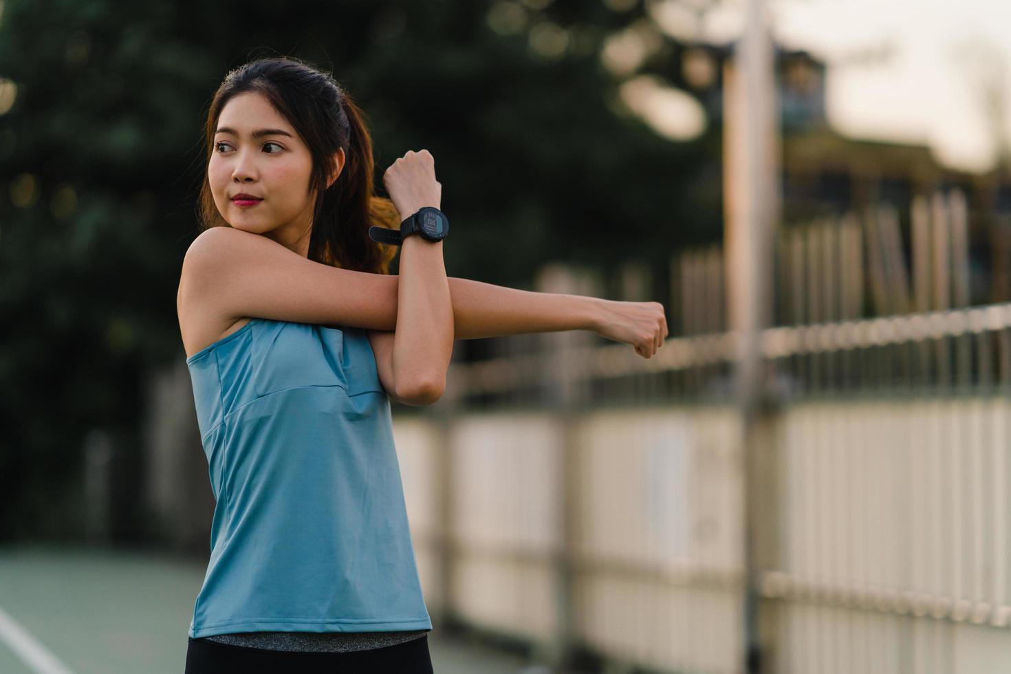 giovane atleta asiatico femmina che si estende dopo una corsa all'aperto foto