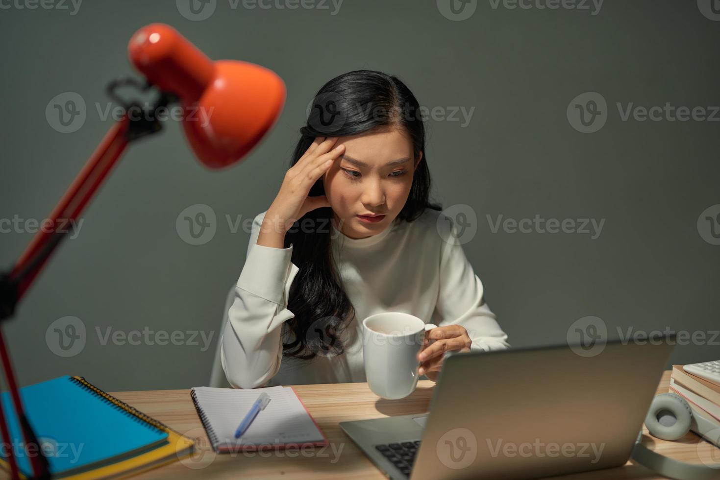 sorridente femmina imprenditore Lavorando a partire dal casa in ritardo a notte foto