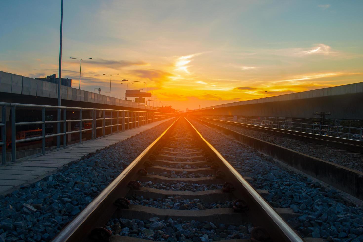 binari ferroviari e luce solare arancione foto