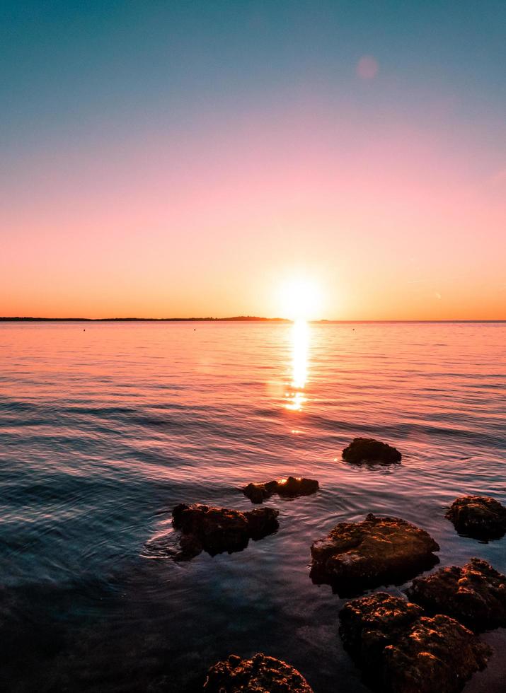 rocce sull'acqua con cielo colorato foto