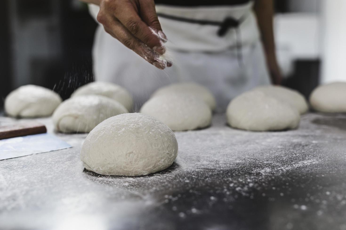 chef spolverare farina sull'impasto foto