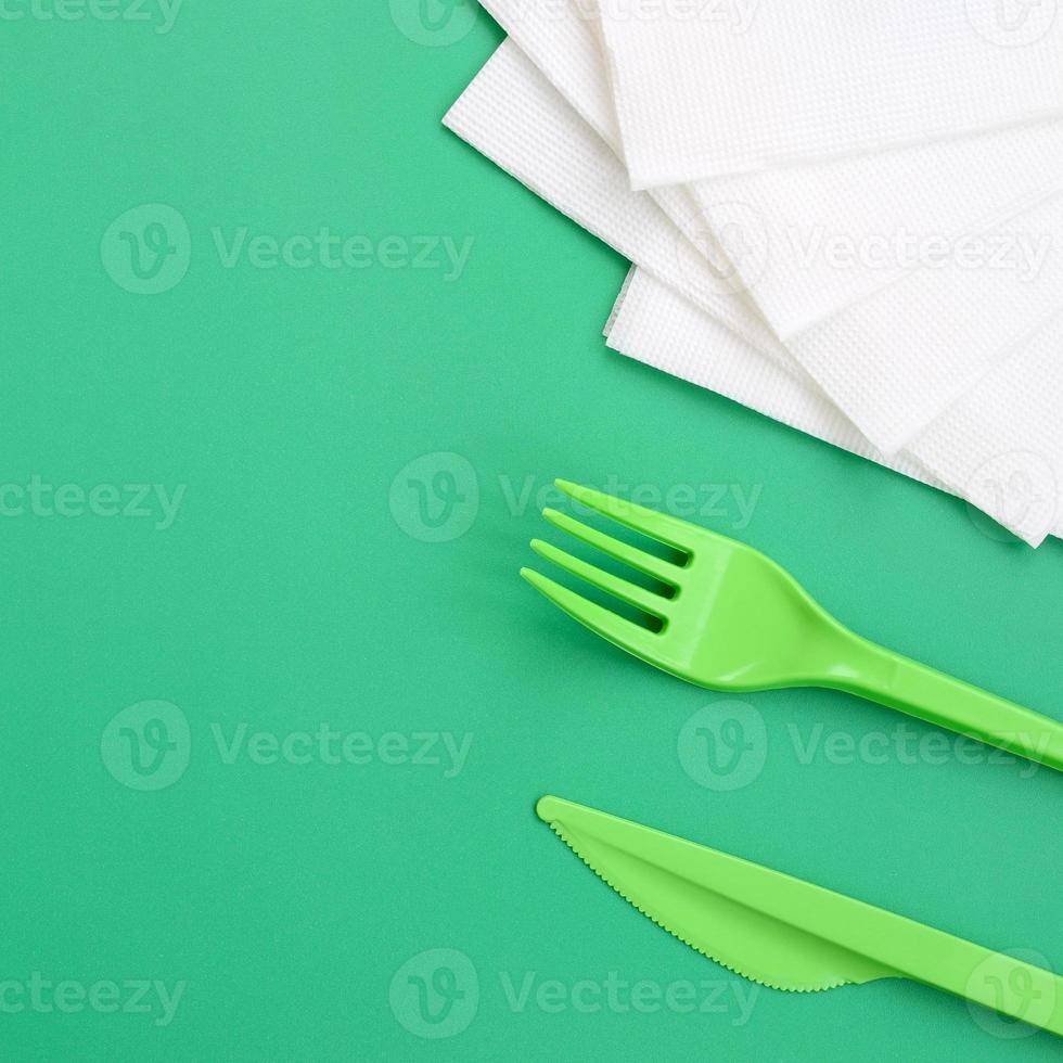 monouso plastica posate verde. plastica forchetta e coltello menzogna su un' verde sfondo superficie Il prossimo per tovaglioli foto