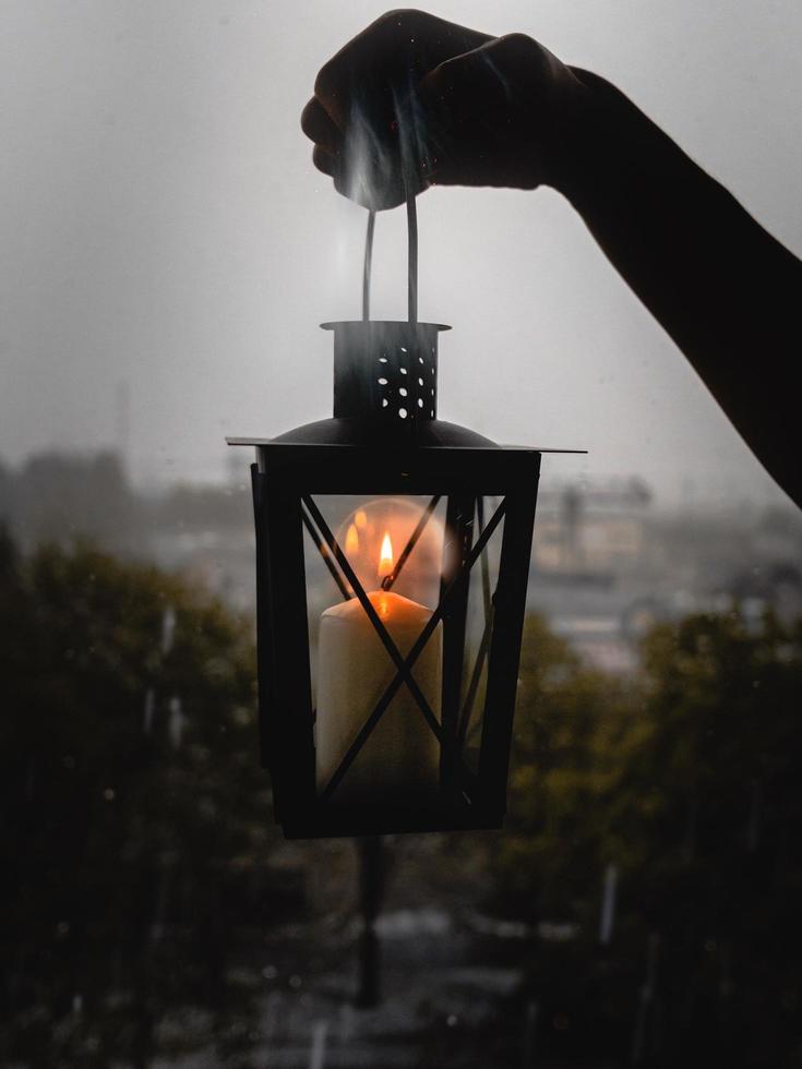 lanterna di candela tenuta vicino alla finestra foto