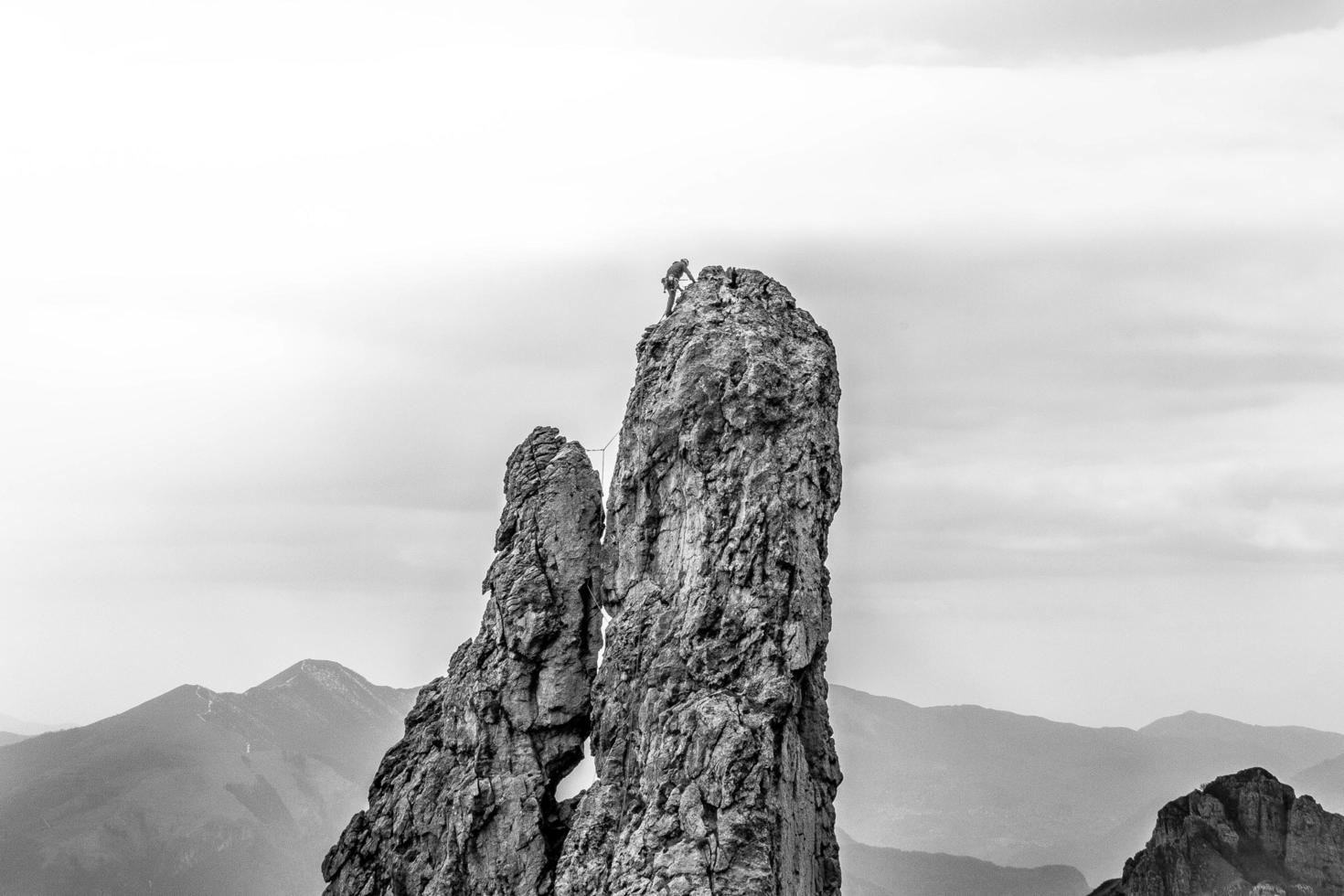 scala di grigi della persona che si arrampica sulla scogliera foto