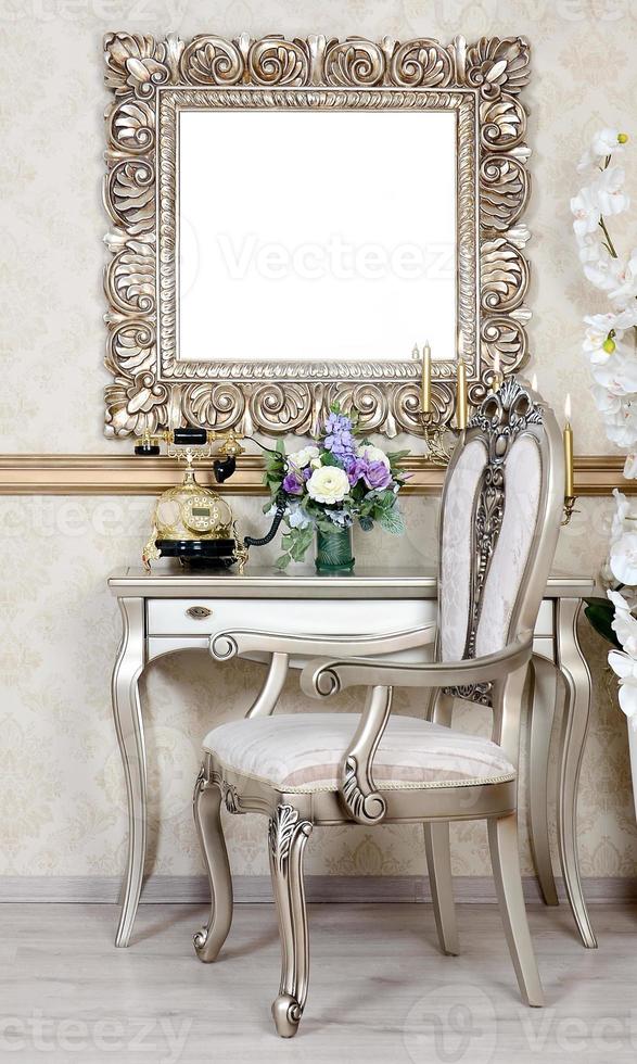 un' frammento di un' retrò interno con un' sedia e tavolo, su quale è un' telefono e un' vaso di fiori. sopra il tavolo si blocca un vuoto immagine telaio per il tuo foto