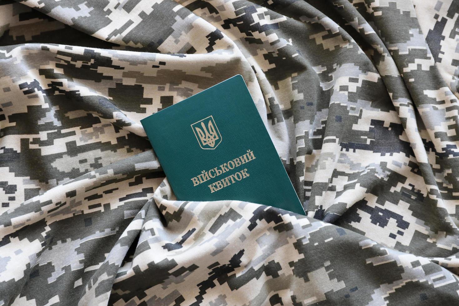 sumy, Ucraina - marzo 20, 2022 ucraino militare id su tessuto con struttura di pixeled camuffare. stoffa con Camo modello nel grigio, Marrone e verde pixel forme con ucraino esercito personale gettone foto
