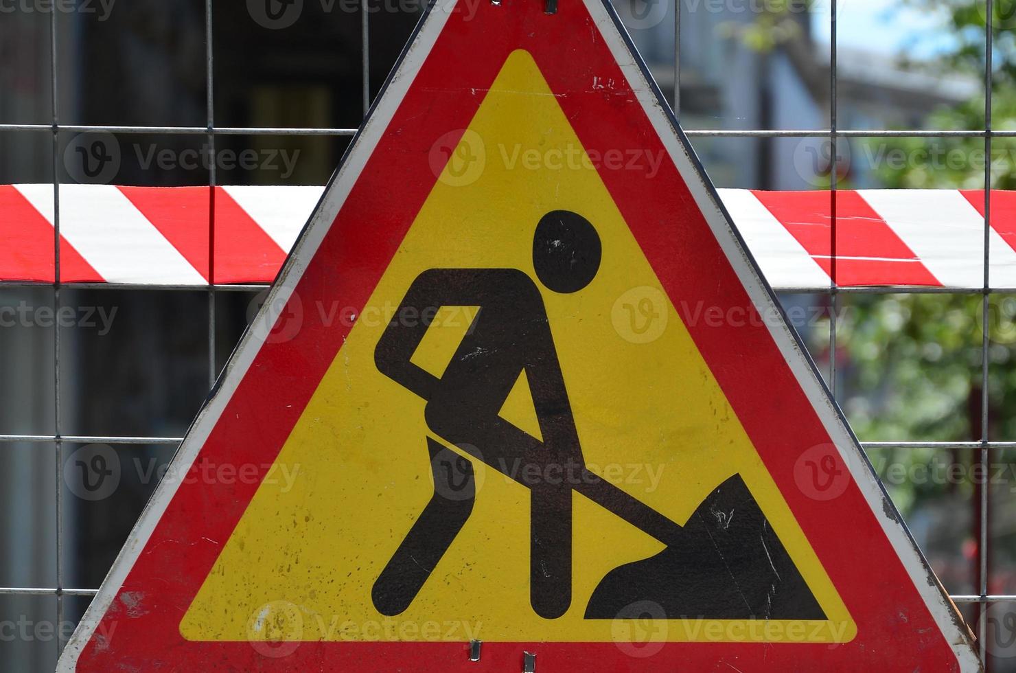 il avvertimento cartello sotto costruzione è allegato per un' metallo maglia recinto con un' rosso e bianca a strisce segnale nastro foto
