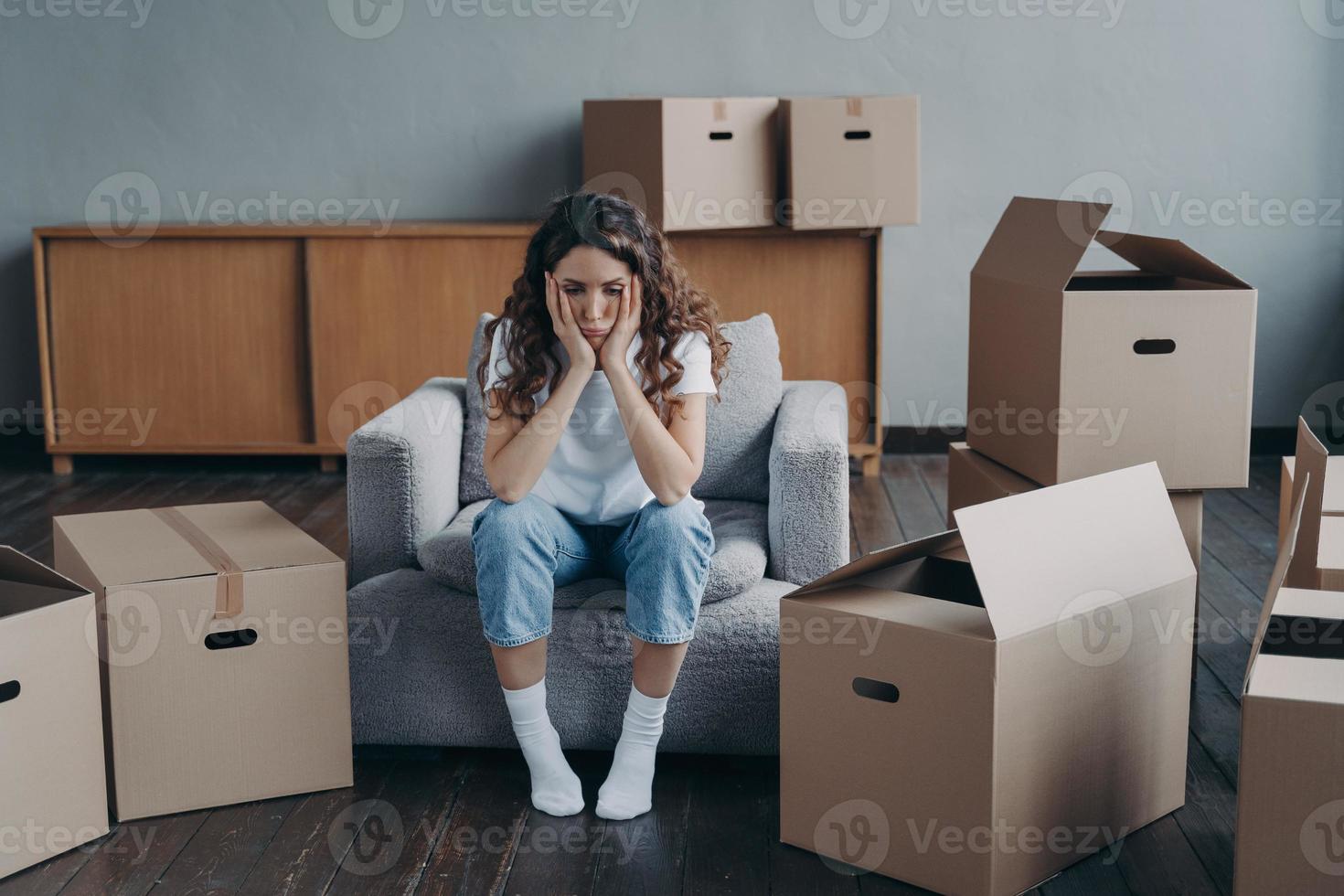 infelice donna è triste perché di delocalizzazione seduta vicino cartone scatole. difficile in movimento giorno, divorzio foto