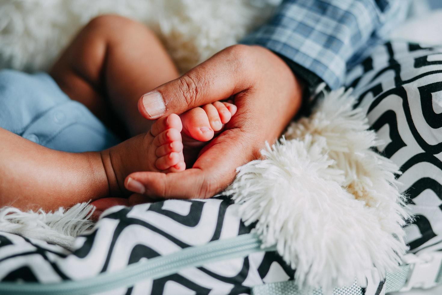 la mano del padre che tiene i piedi del bambino foto