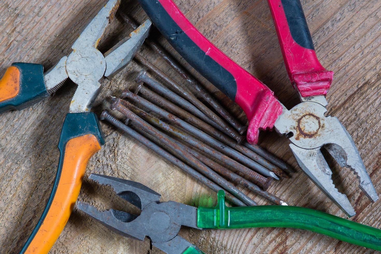 diverso utensili su un' di legno sfondo. chiodo, pinze foto