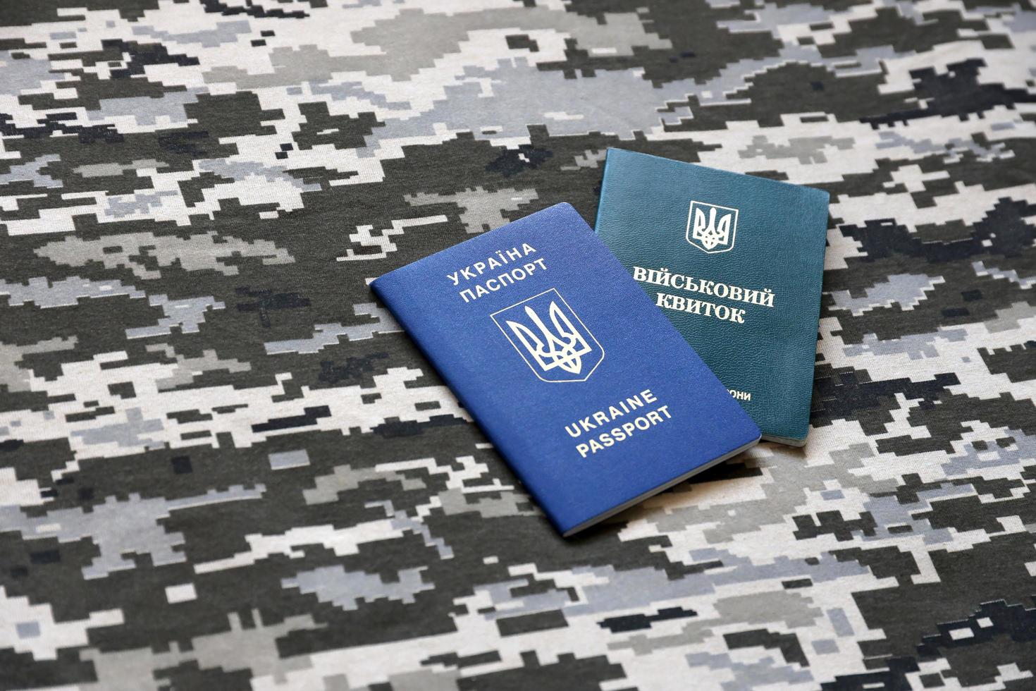 sumy, Ucraina - marzo 20, 2022 ucraino militare id e straniero passaporto su tessuto con struttura di pixeled camuffare. foto