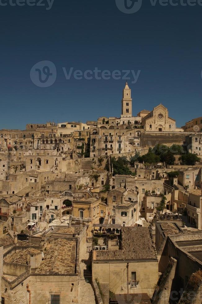 Visualizza a vecchio edifici, muri, tetti e roccia con religioso attraversare nel antico cittadina, sassi de matera, Italia. foto