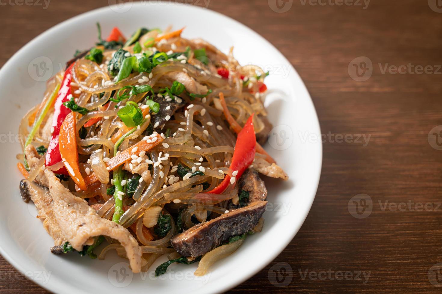 japchae o vermicelli coreani saltati in padella con verdure e maiale conditi con sesamo bianco foto