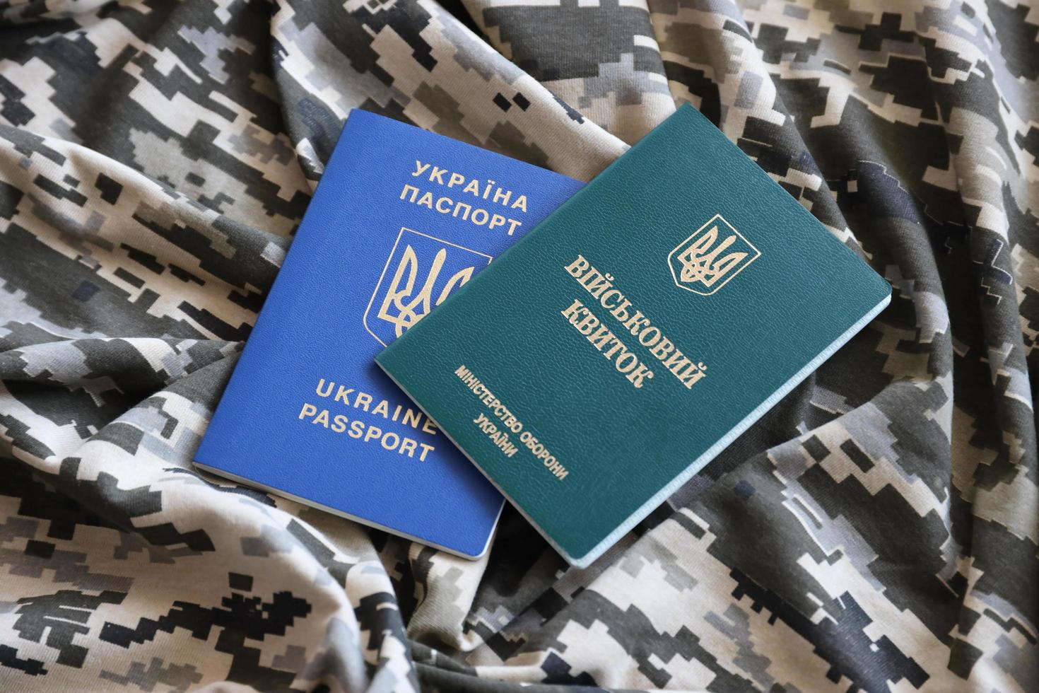 sumy, Ucraina - marzo 20, 2022 ucraino militare id e straniero passaporto su tessuto con struttura di pixeled camuffare. foto