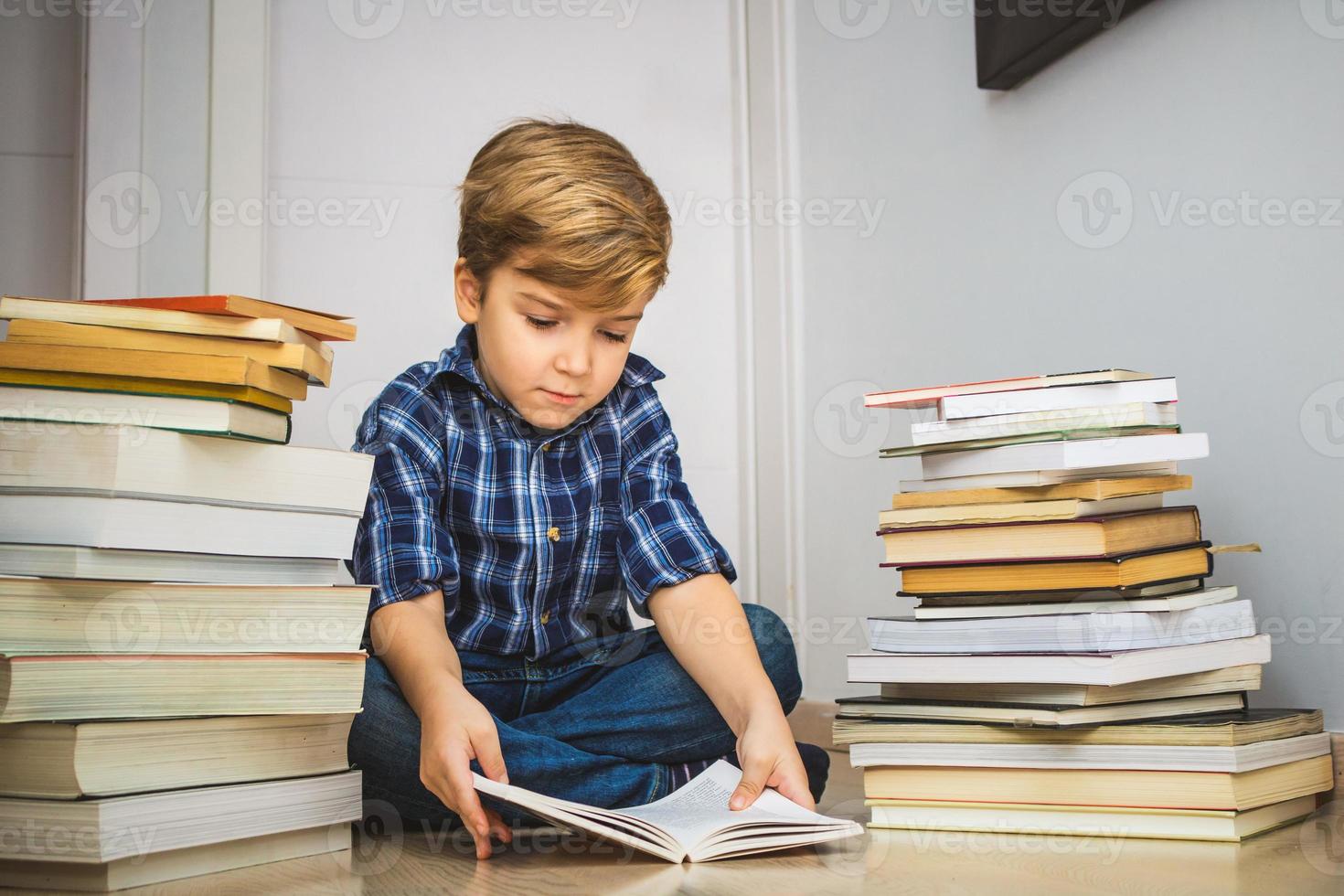 poco ragazzo lettura tra pila di libri. foto