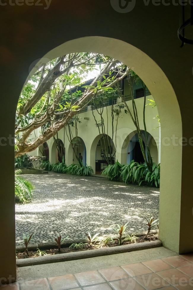 coloniale architettura, archi circondato di vegetazione, giocare di leggero e ombre dentro il spazio, naturale materiale foto