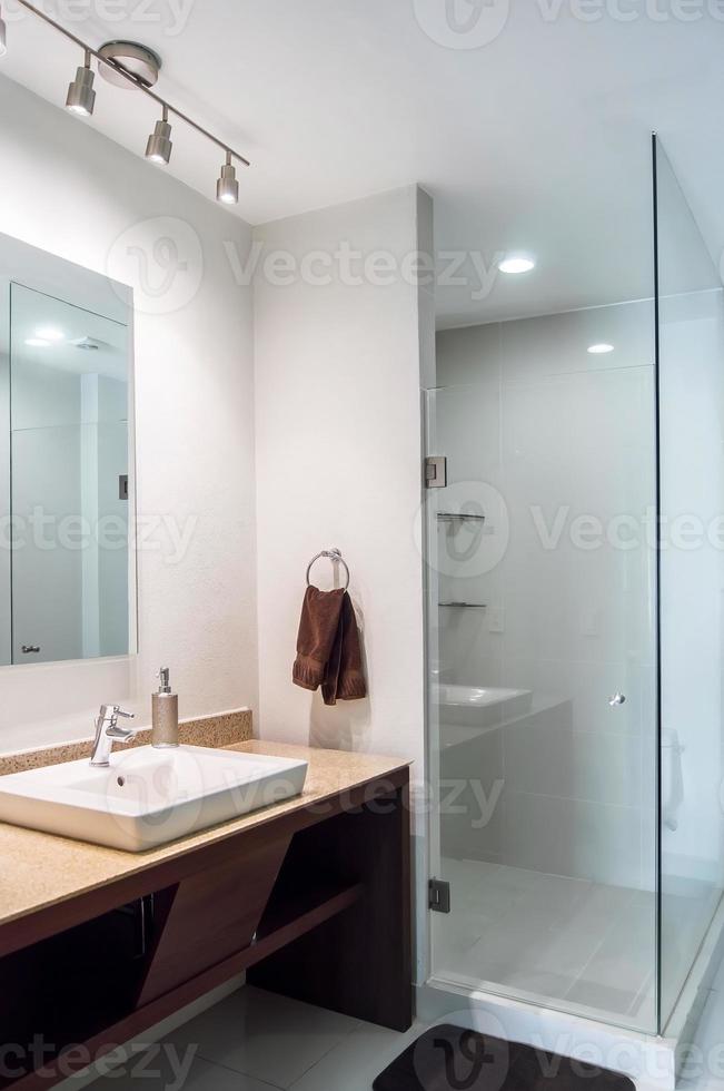 bagno con lusso finiture, principale specchio con guidato leggero a partire dal dietro, bianca ceramica lavabo foto