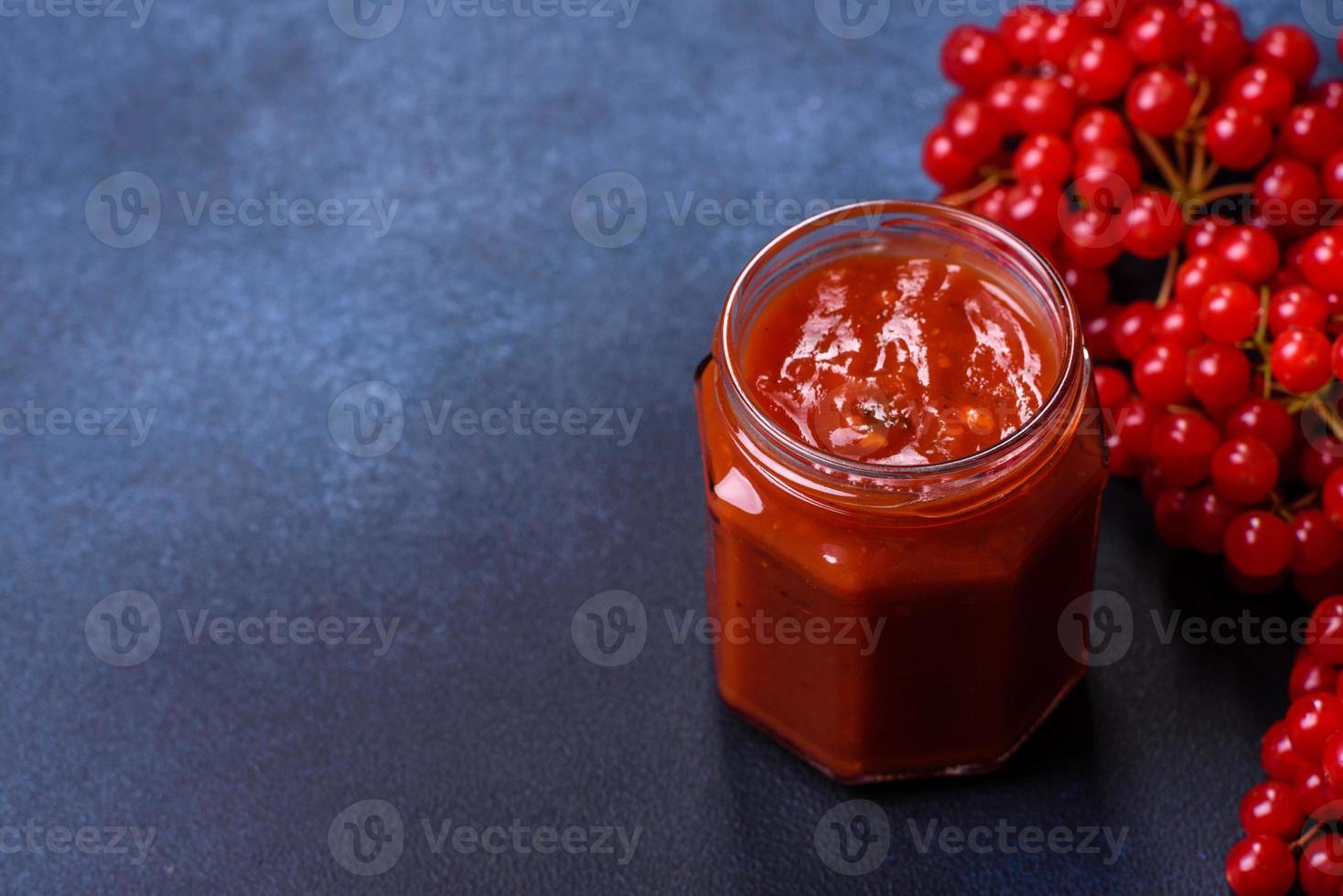 Viburnum frutta marmellata nel un' bicchiere vaso su un' buio calcestruzzo sfondo foto