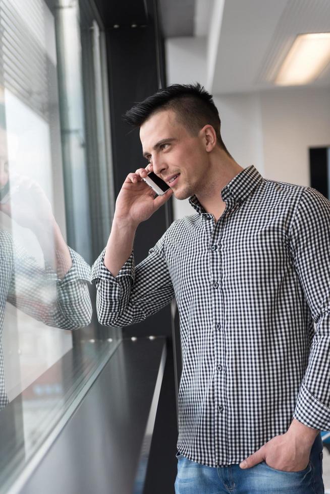 giovane attività commerciale uomo A proposito di su inteligente Telefono a ufficio foto