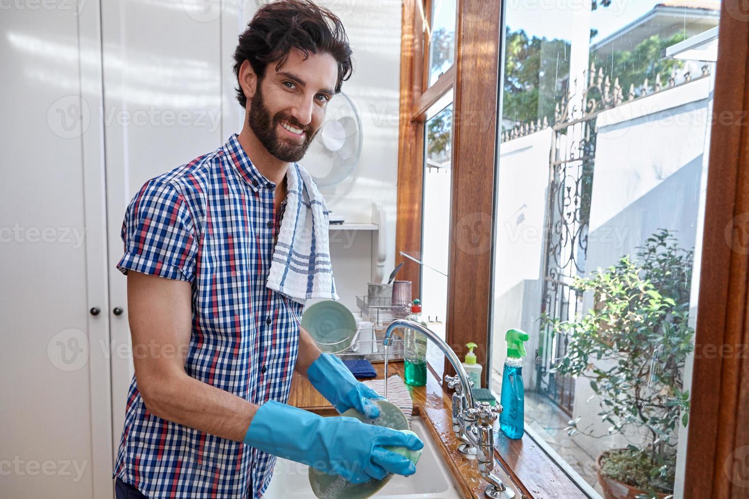 uomo barbuto lavare i piatti in un lavandino con i guanti foto
