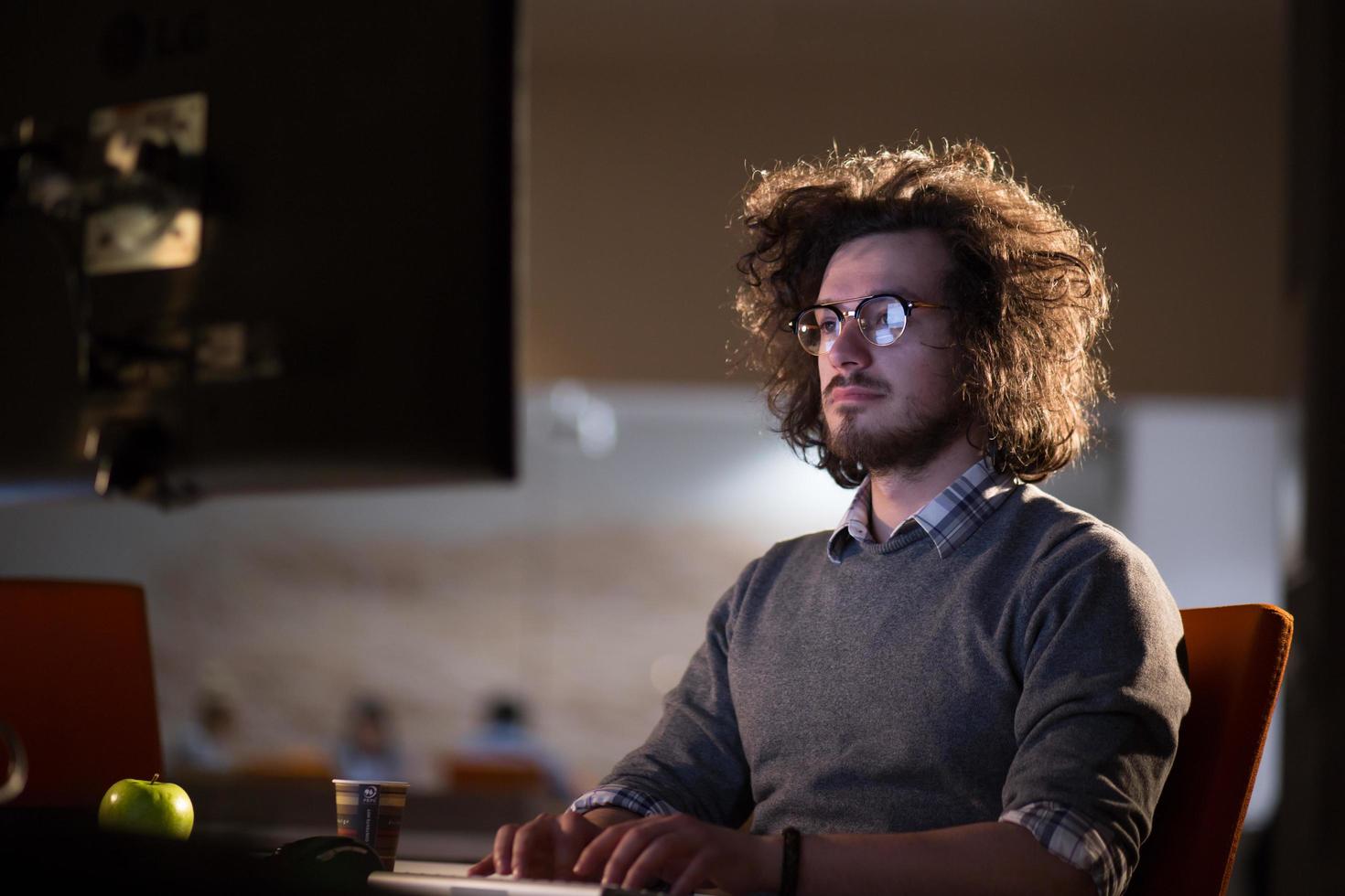 uomo Lavorando su computer nel buio ufficio foto